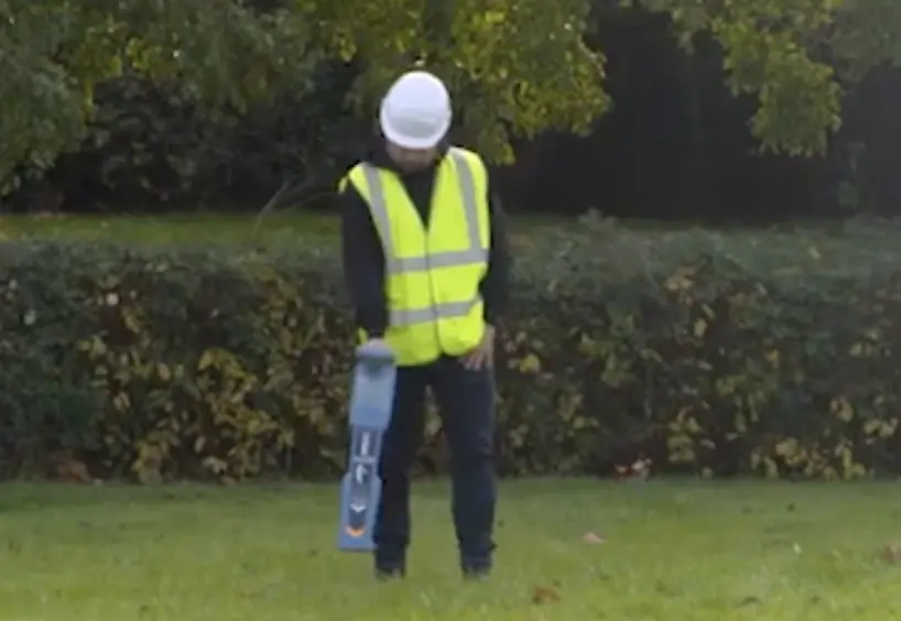 A man in yellow vest holding a skateboard.