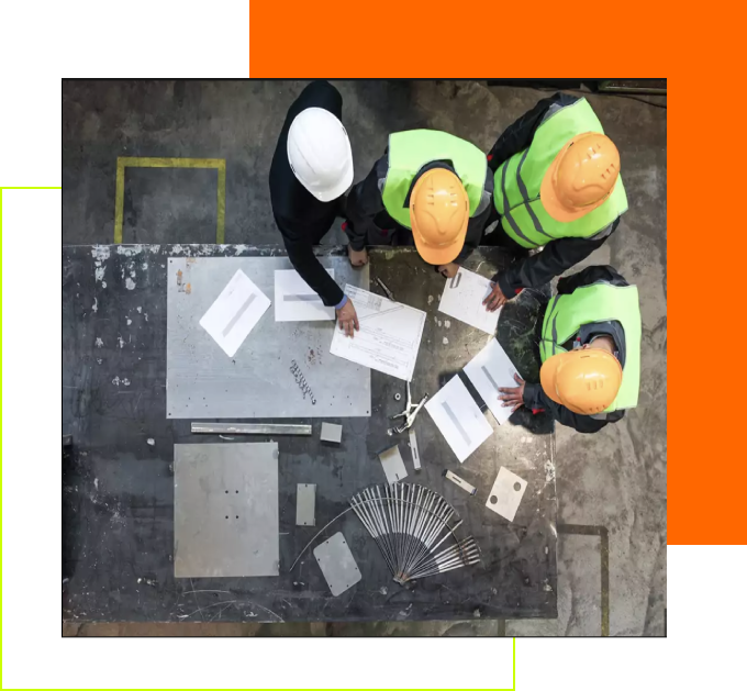 Three construction workers looking at papers on a table.